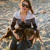 Mawoo customer holding two Australian Shepherd puppies on sandy ground